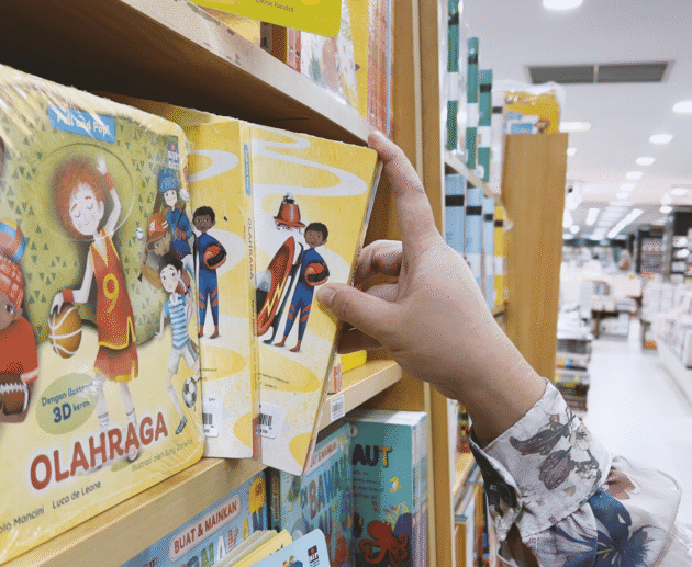 Reader picking a sports book from a bookstore shelf